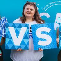 three students posing in front of CAB backdrop at Laker Kickoff photo booth and displaying GVSU letters